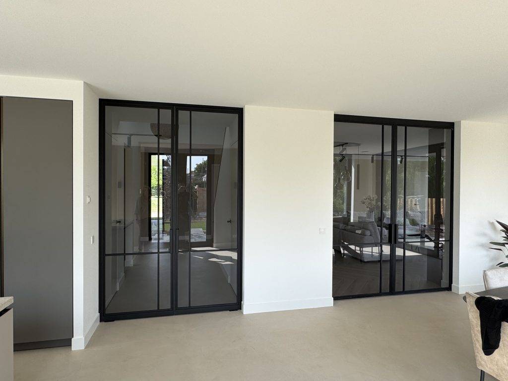 Moderne woning met grote glazen schuifdeuren, natuurlijk licht, lichte vloer en groene tuin.