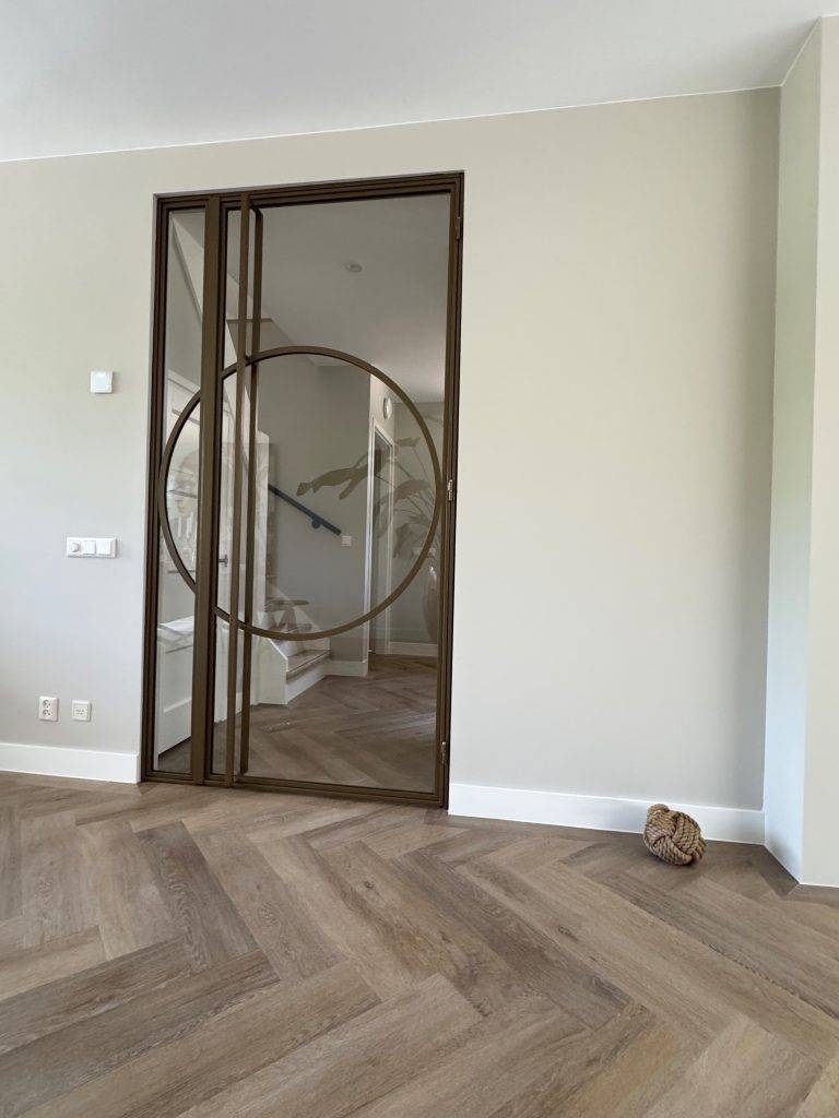 Modern interieur met ronde dubbele deur, houten vloer en minimalistische, warme uitstraling.