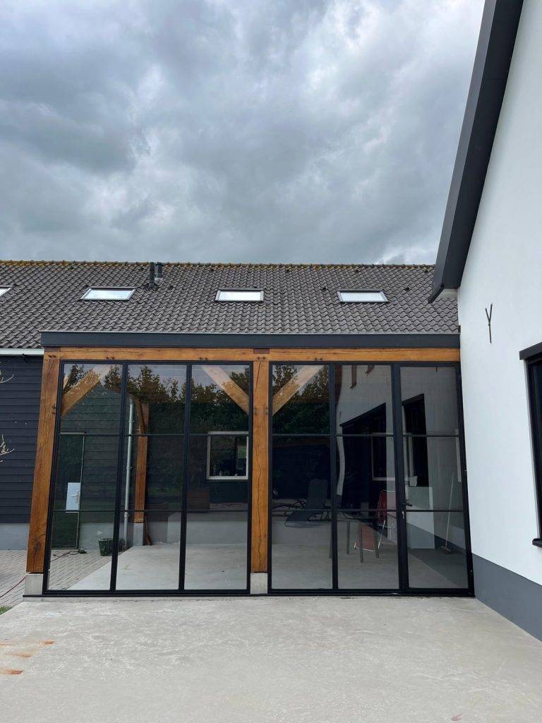 Moderne woning met glazen gevel, houten accenten en natuur-inspirerende architectuur.