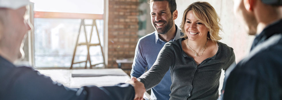 Collega’s schudden handen in industrieel kantoor, bouwproject, teamwork, samenwerking, positieve werksfeer, zakelijke meeting.